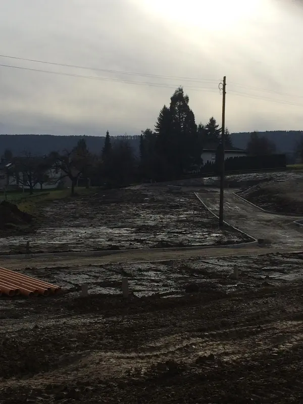 Abgeschobene Erdfläche mit Fahrspuren im Morgenlicht, vorbereitet für den weiteren Aufbau