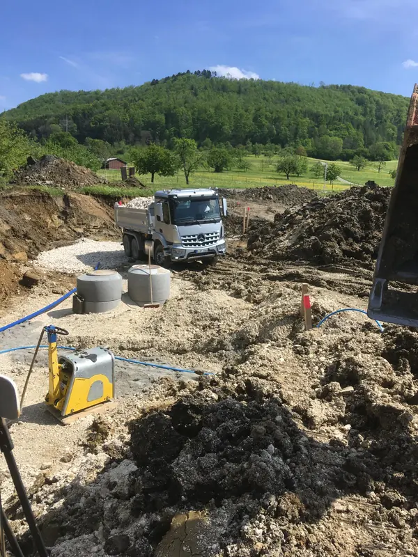 Betonschachtringe und Rüttelplatte auf einer Kanalbaustelle im Erschließungsgebiet