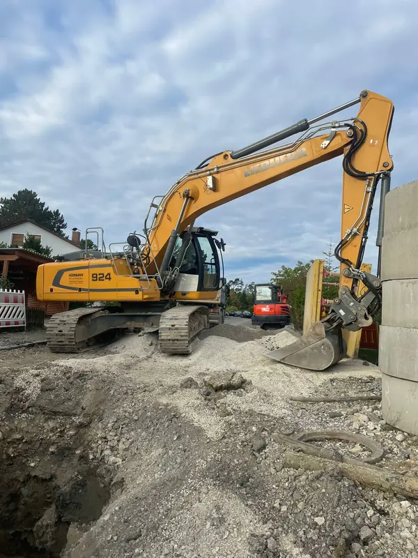 Liebherr 924 Mobilbagger arbeitet auf einer Schotterfläche neben einem Wohnhaus
