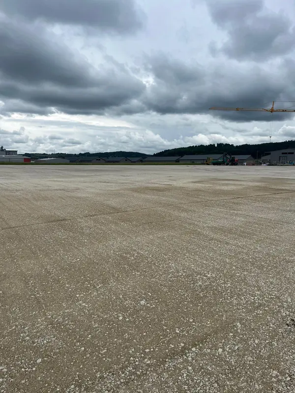 Weitläufige, fertig verdichtete Baufläche unter bewölktem Himmel