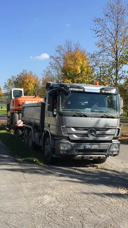 Mercedes Kipper mit Anhänger des Bauunternehmens Herrmann am Straßenrand