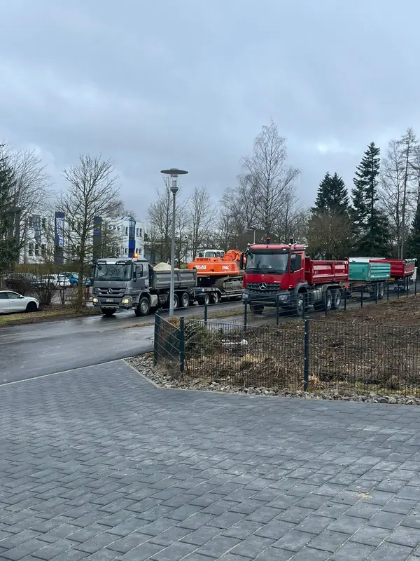Mehrere Lastwagen und Kipper des Unternehmens stehen bereit auf einer Hoffläche