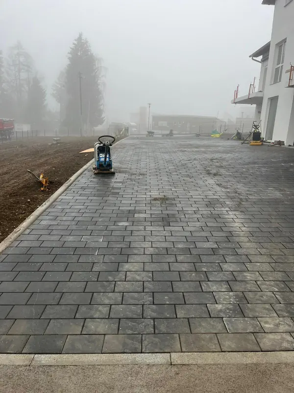 Fertig verlegte Pflasterfläche mit Rüttelplatte an einem nebligen Morgen