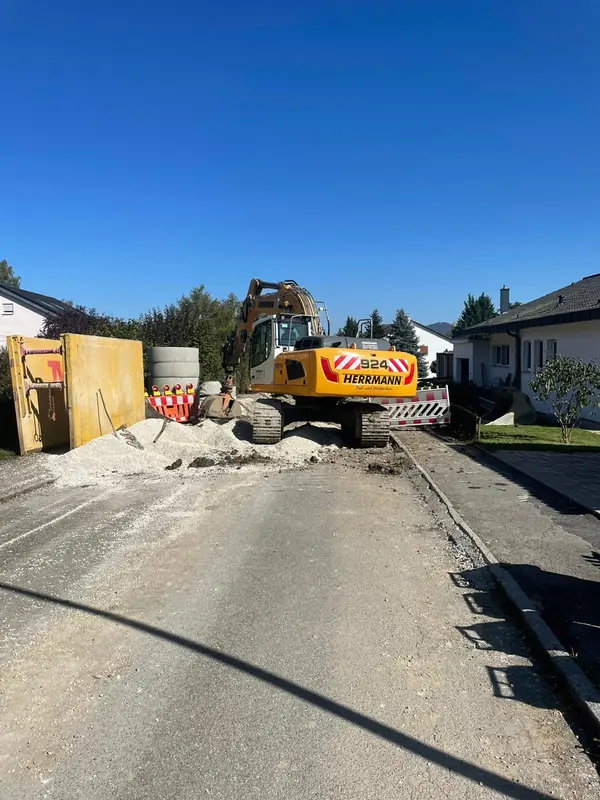 Abgesicherte Kanalbaustelle mit Bagger und Absperrung in einer Ortsstraße