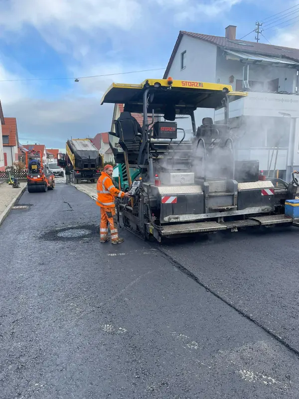 Asphaltfertiger und Bauarbeiter beim Einbau der Asphaltdeckschicht