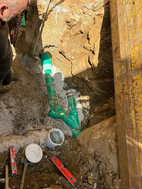 Grüne Wasserleitungen mit Formteilen und Absperrarmaturen im offenen Graben